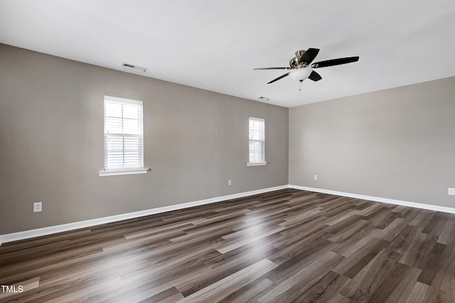 unfurnished room with visible vents, a ceiling fan, baseboards, and dark wood-style flooring