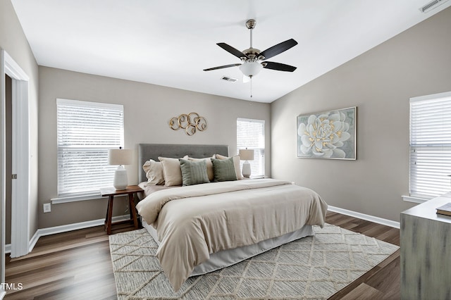 bedroom featuring vaulted ceiling, visible vents, baseboards, and wood finished floors