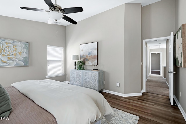 bedroom featuring baseboards, attic access, wood finished floors, and a ceiling fan