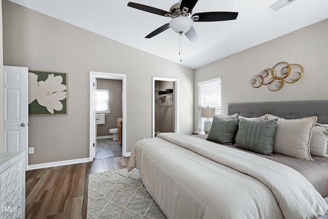 bedroom featuring baseboards, multiple windows, wood finished floors, and vaulted ceiling