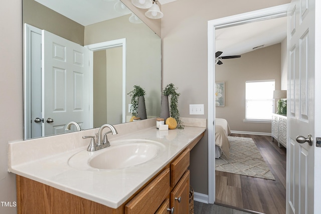 bathroom with vanity, wood finished floors, baseboards, ceiling fan, and connected bathroom