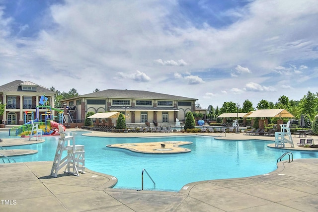 pool with a patio area, a water slide, and a water play area