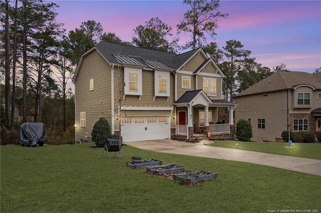 view of front of home featuring a standing seam roof, a porch, a yard, and driveway