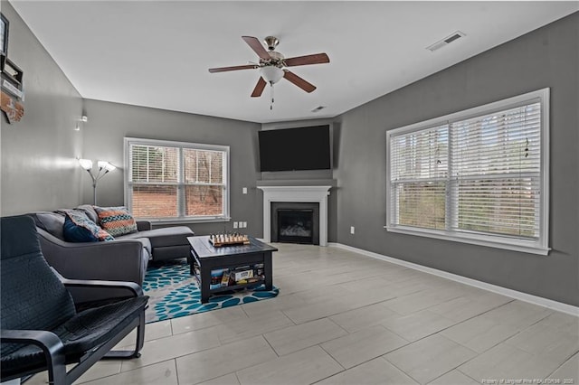 living room with visible vents, ceiling fan, a fireplace, and baseboards