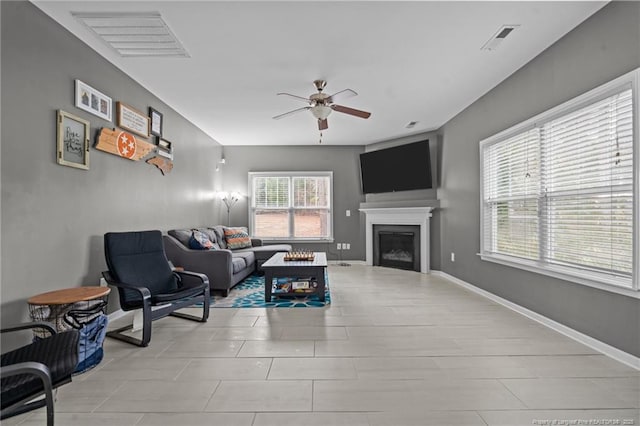 living area with visible vents, baseboards, ceiling fan, and a fireplace