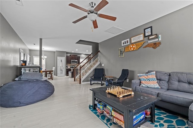 living area with stairway, ceiling fan with notable chandelier, and visible vents