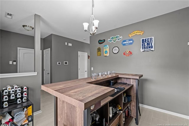 kitchen with decorative light fixtures, visible vents, baseboards, and a notable chandelier