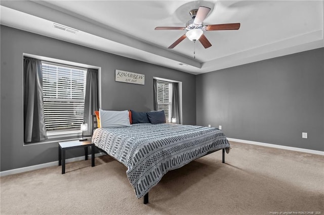 carpeted bedroom featuring visible vents, a ceiling fan, a raised ceiling, and baseboards