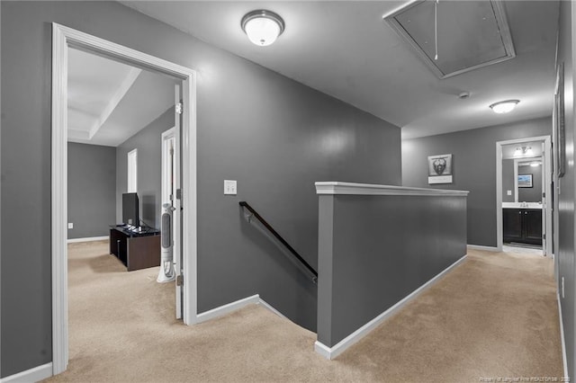 corridor with an upstairs landing, carpet flooring, attic access, and baseboards