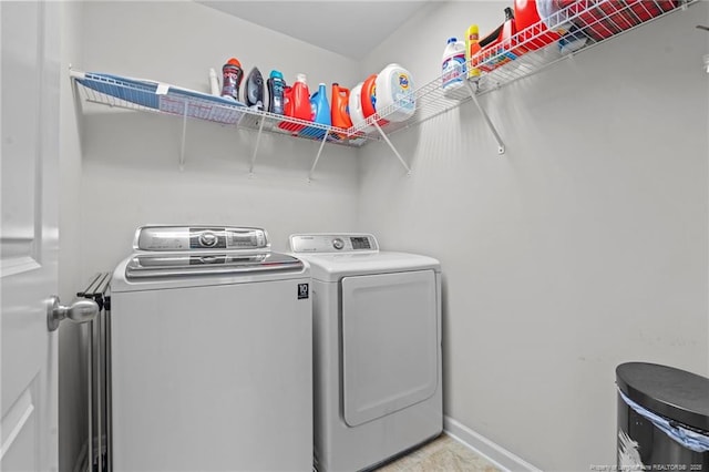 clothes washing area featuring washing machine and clothes dryer, laundry area, and baseboards