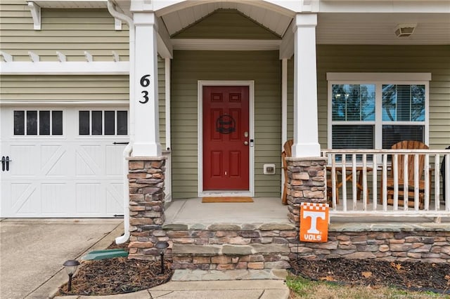 property entrance with aphalt driveway, covered porch, and stone siding