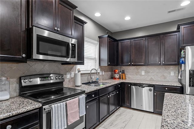 kitchen with visible vents, a sink, light stone counters, stainless steel appliances, and dark brown cabinetry