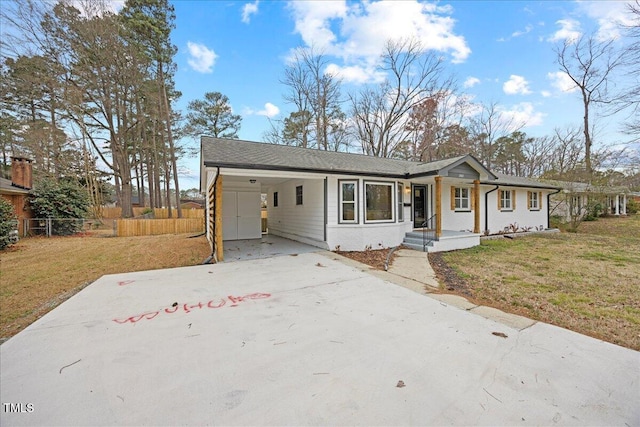 ranch-style house with an attached carport, concrete driveway, a front lawn, and fence