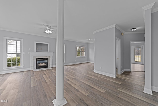 unfurnished living room featuring a wealth of natural light, a premium fireplace, ceiling fan, and dark wood-style flooring