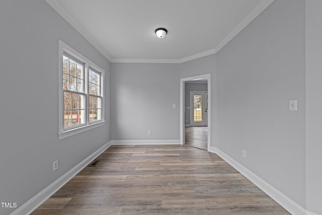 empty room with wood finished floors, a healthy amount of sunlight, and ornamental molding