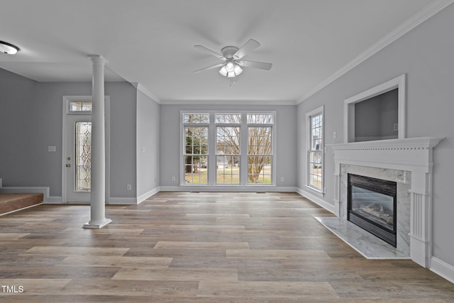 unfurnished living room featuring a fireplace, wood finished floors, baseboards, and ornate columns