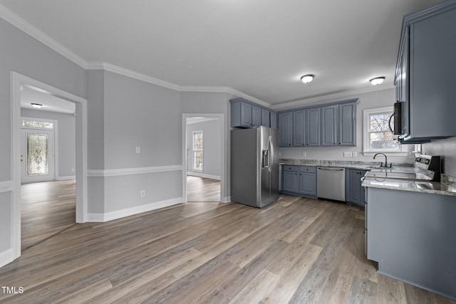 kitchen with crown molding, light stone counters, light wood-style floors, and stainless steel appliances