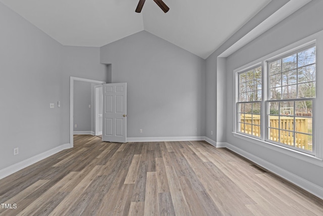 empty room with visible vents, baseboards, vaulted ceiling, wood finished floors, and a ceiling fan