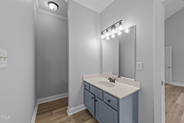 bathroom with vanity, wood finished floors, baseboards, and ornamental molding