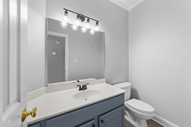 bathroom with toilet, wood finished floors, crown molding, baseboards, and vanity