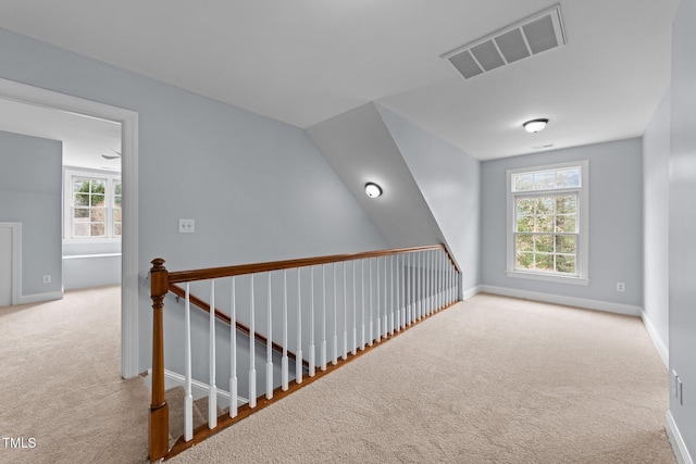 corridor featuring visible vents, baseboards, and carpet