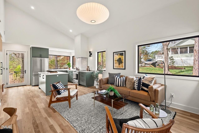 living room with recessed lighting, baseboards, light wood finished floors, and high vaulted ceiling