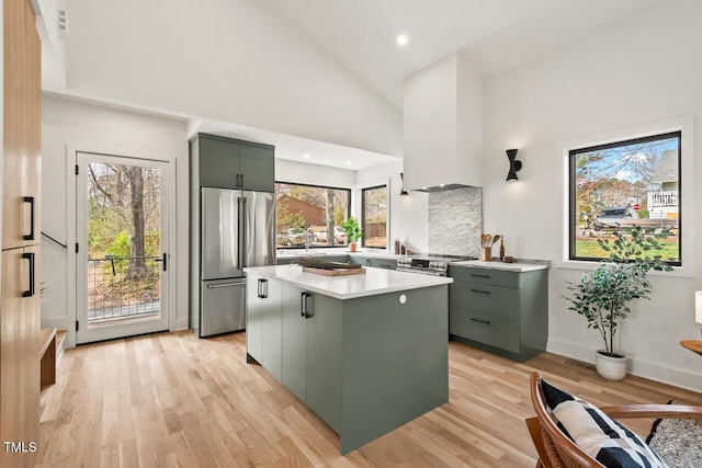 kitchen with a center island, stainless steel appliances, light wood-style floors, green cabinets, and light countertops