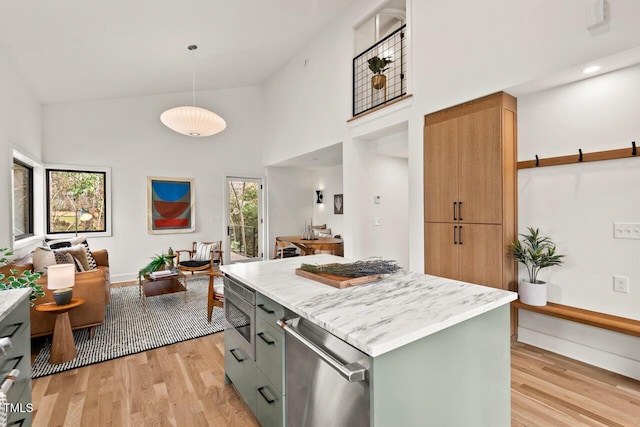 kitchen featuring light wood finished floors, hanging light fixtures, a towering ceiling, open floor plan, and a center island