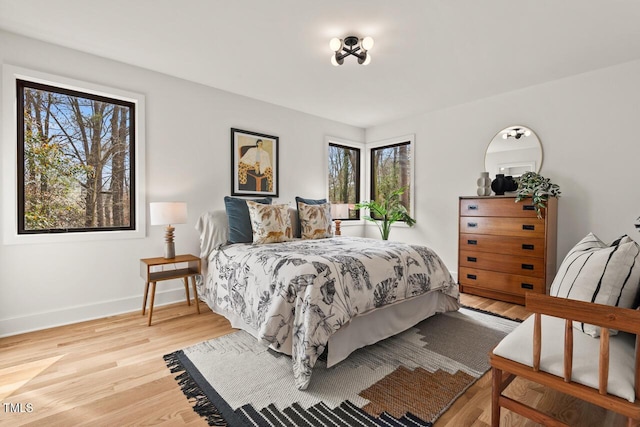 bedroom with multiple windows, baseboards, and wood finished floors