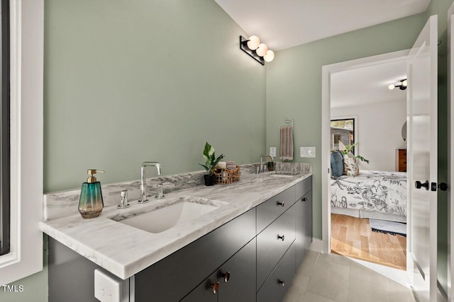 ensuite bathroom with double vanity, wood finished floors, ensuite bathroom, and a sink