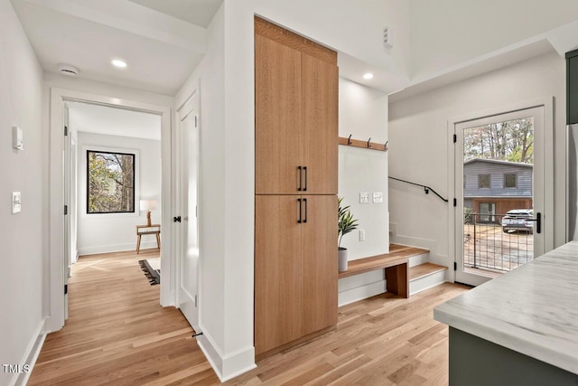 hallway with light wood finished floors, stairway, recessed lighting, and baseboards