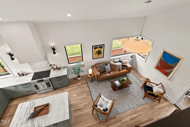 living area featuring lofted ceiling, recessed lighting, baseboards, and light wood-type flooring