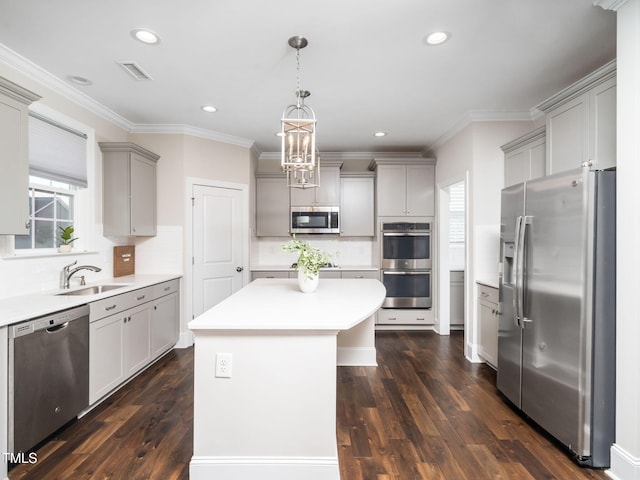 kitchen with gray cabinets, a kitchen island, stainless steel appliances, light countertops, and dark wood-style flooring