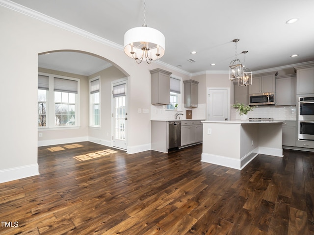 kitchen featuring stainless steel appliances, arched walkways, gray cabinetry, and an inviting chandelier