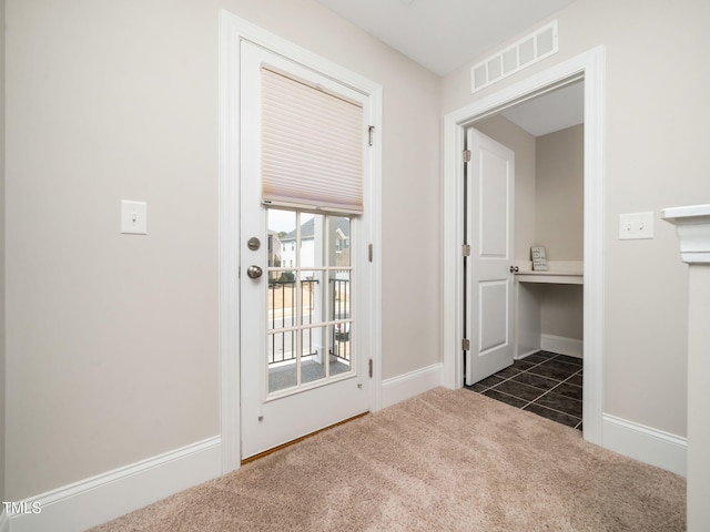 entryway featuring dark tile patterned flooring, baseboards, visible vents, and dark colored carpet