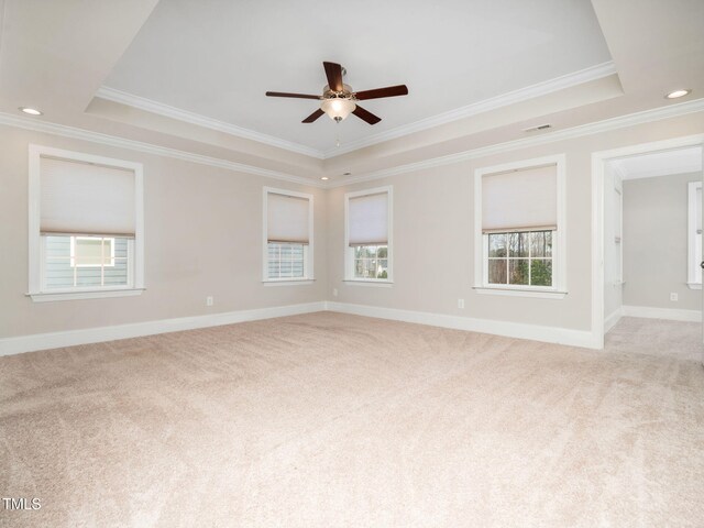 unfurnished room with light colored carpet, baseboards, a raised ceiling, and ceiling fan