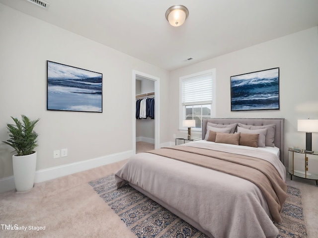 carpeted bedroom with a spacious closet, visible vents, a closet, and baseboards