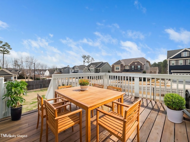 wooden deck featuring outdoor dining area, fence, and a residential view