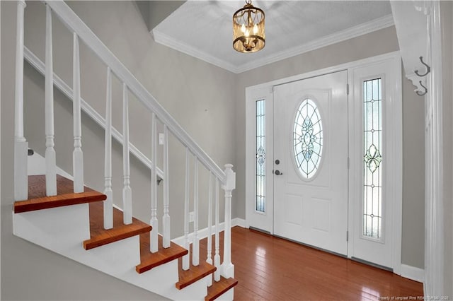 entryway featuring crown molding, baseboards, stairs, an inviting chandelier, and hardwood / wood-style flooring