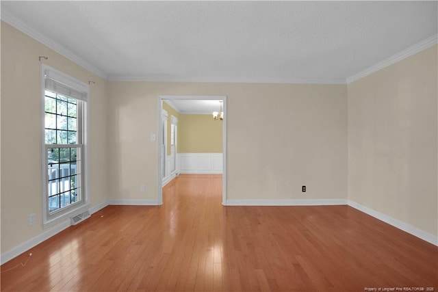 unfurnished room with baseboards, visible vents, light wood-style floors, crown molding, and a chandelier