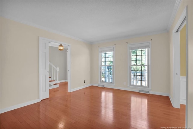 unfurnished room with hardwood / wood-style floors, visible vents, baseboards, stairs, and crown molding