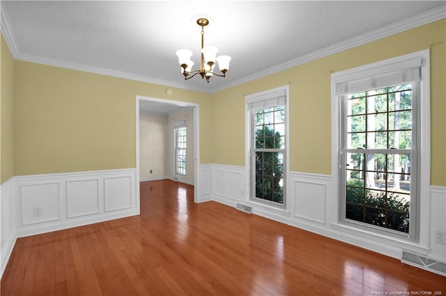 unfurnished dining area featuring visible vents, plenty of natural light, an inviting chandelier, and hardwood / wood-style floors