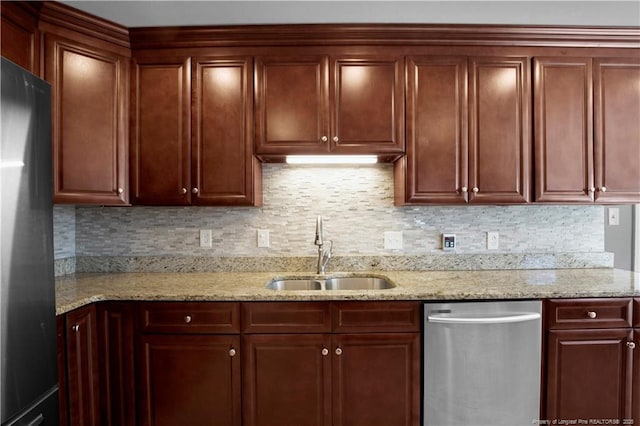 kitchen featuring dishwasher, backsplash, freestanding refrigerator, and a sink