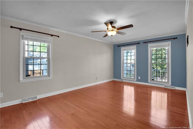 empty room featuring visible vents, a textured ceiling, crown molding, and hardwood / wood-style flooring