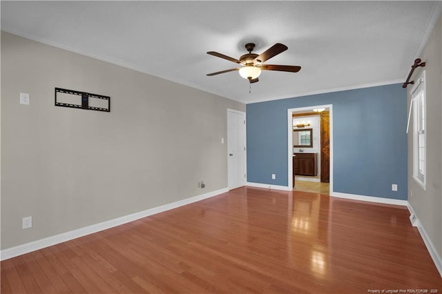 spare room featuring crown molding, baseboards, a wealth of natural light, wood finished floors, and a ceiling fan