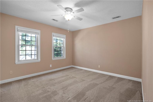 carpeted empty room with visible vents, ceiling fan, a textured ceiling, and baseboards