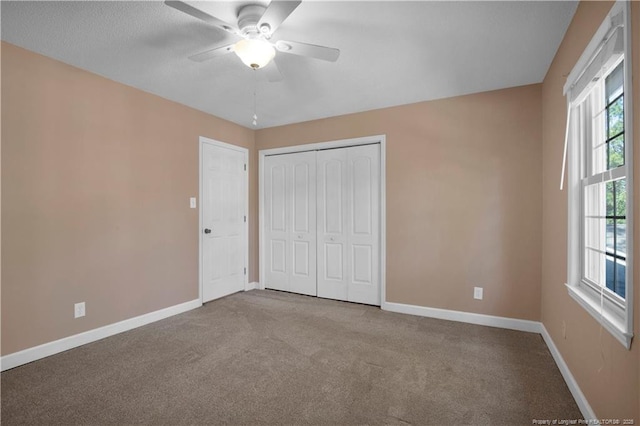 unfurnished bedroom featuring carpet flooring, a ceiling fan, baseboards, and a closet