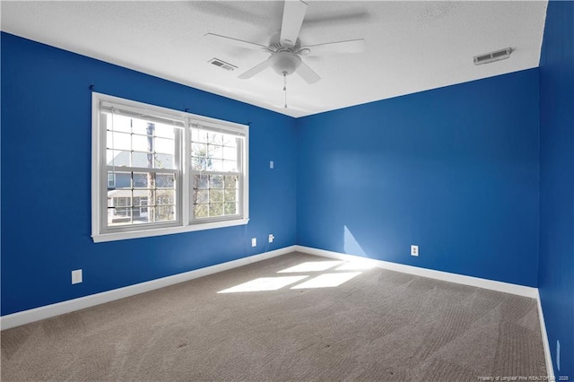 carpeted empty room featuring visible vents, a textured ceiling, baseboards, and ceiling fan