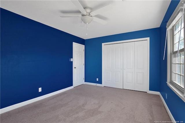 unfurnished bedroom featuring a closet, carpet flooring, a ceiling fan, and baseboards