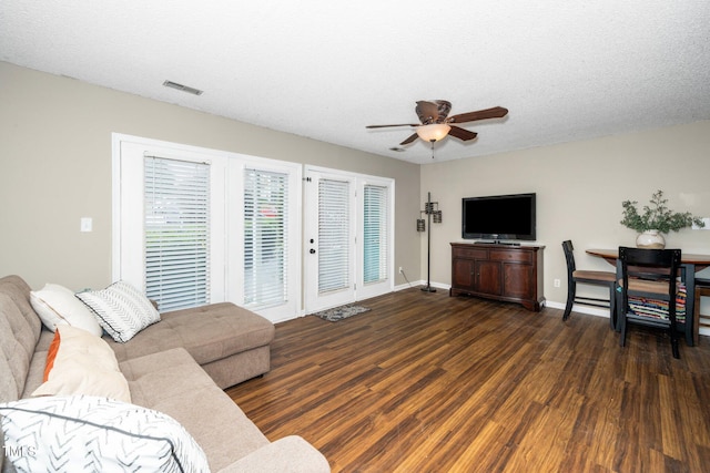 living room featuring visible vents, baseboards, ceiling fan, wood finished floors, and a textured ceiling